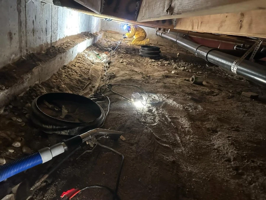 Building maintenance worker repairing a leaking pipe behind an apartment wall