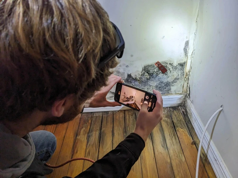 Tenant photographing mold on an apartment wall to document the issue